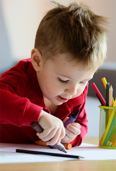 young caucasian boy coloring at table